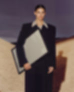 A cinematic framed poster mockup featuring a model in a desert landscape at twilight.