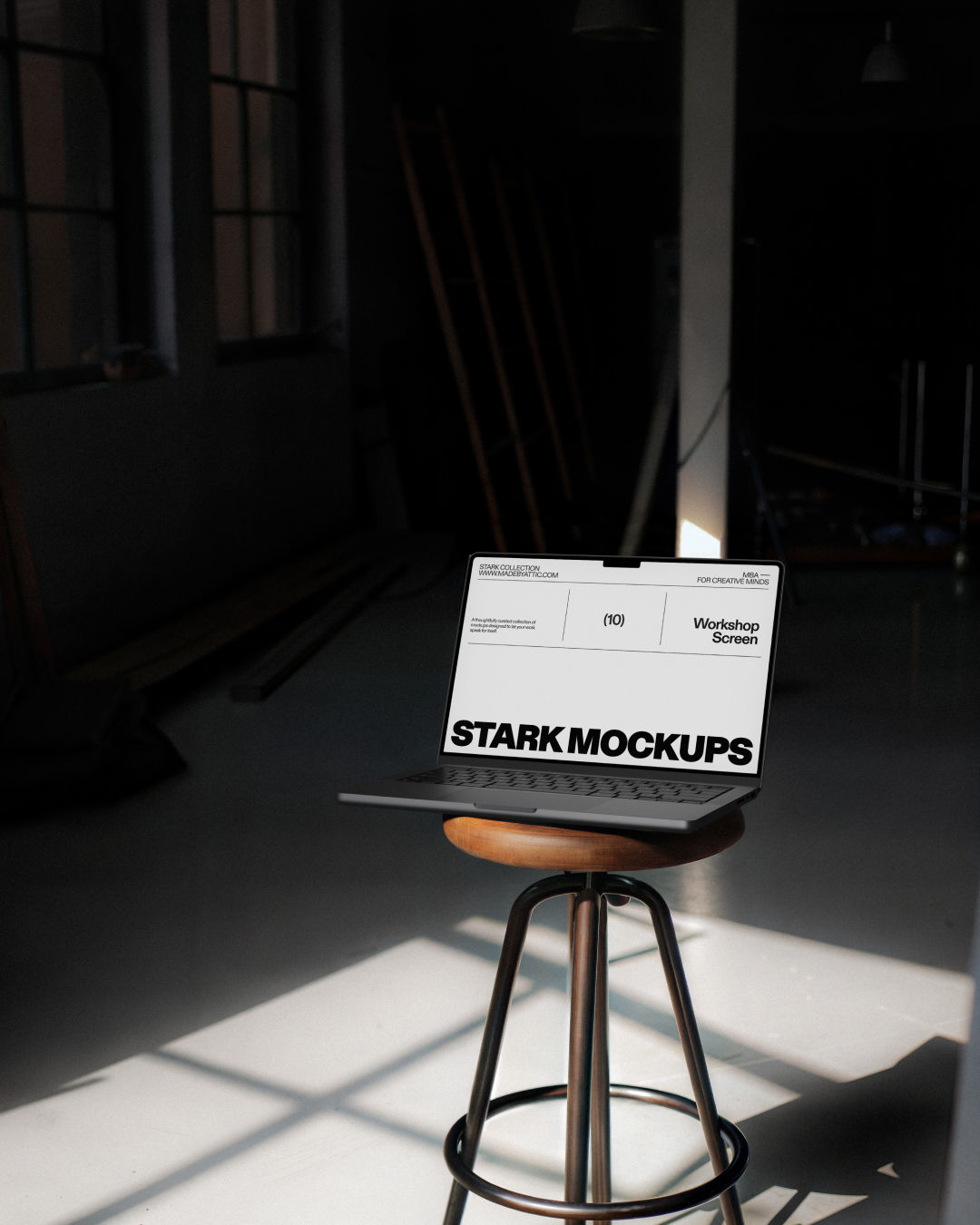 A high-fidelity brutalist macbook mockup resting on a round wooden stool in a dark, high-contrast workshop.
