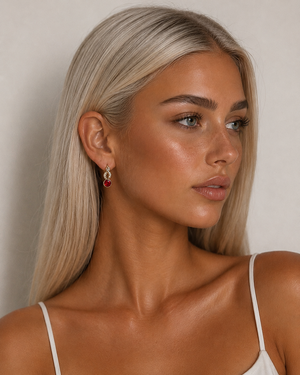 Gold-plated earrings with a red crystal worn by a model