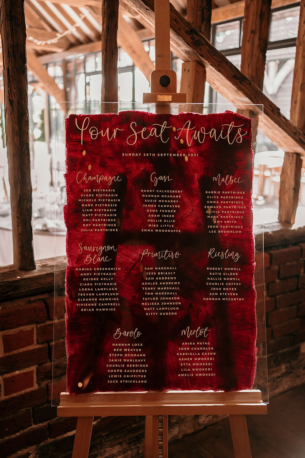 Table plan with a watercolour burgundy background with calligraphy placed on a wooden easel