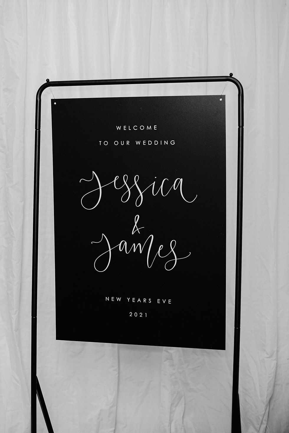 Welcome sign with white calligraphy and text on a black background
