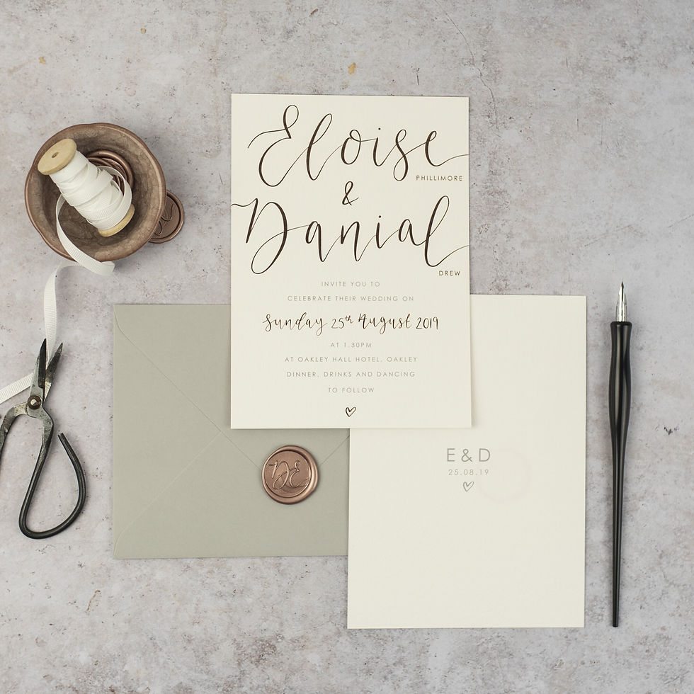 Wedding invitation with rose gold foil calligraphy and a heart detail on crisp white card with a wax seal on the grey envelope