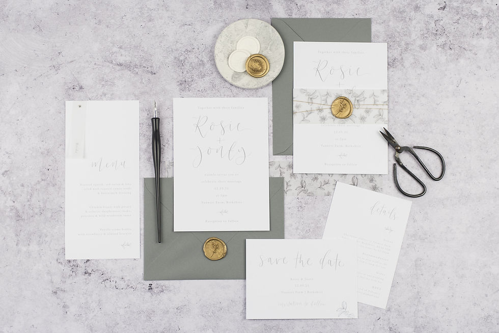 A wedding stationery collection with a grey foliage bellyband, grey calligraphy and gold wax seals.