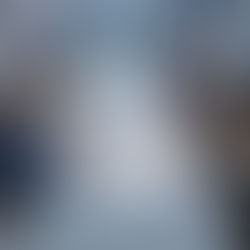 A diverse group of business professionals sitting around a conference table in a modern high-rise office, smiling and discussing documents and charts during a meeting.