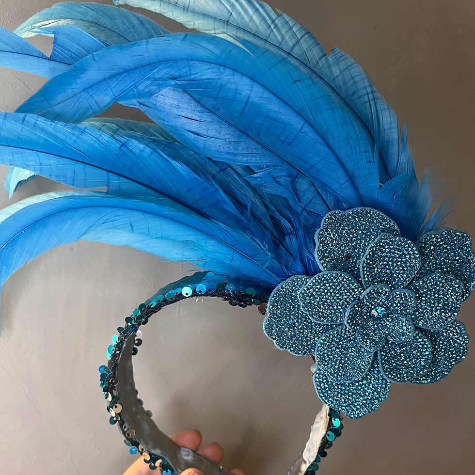 iara de Carnaval com base de lantejoulas azul e prata, detalhe central de flor em strass azul e acabamento com penas azuis.