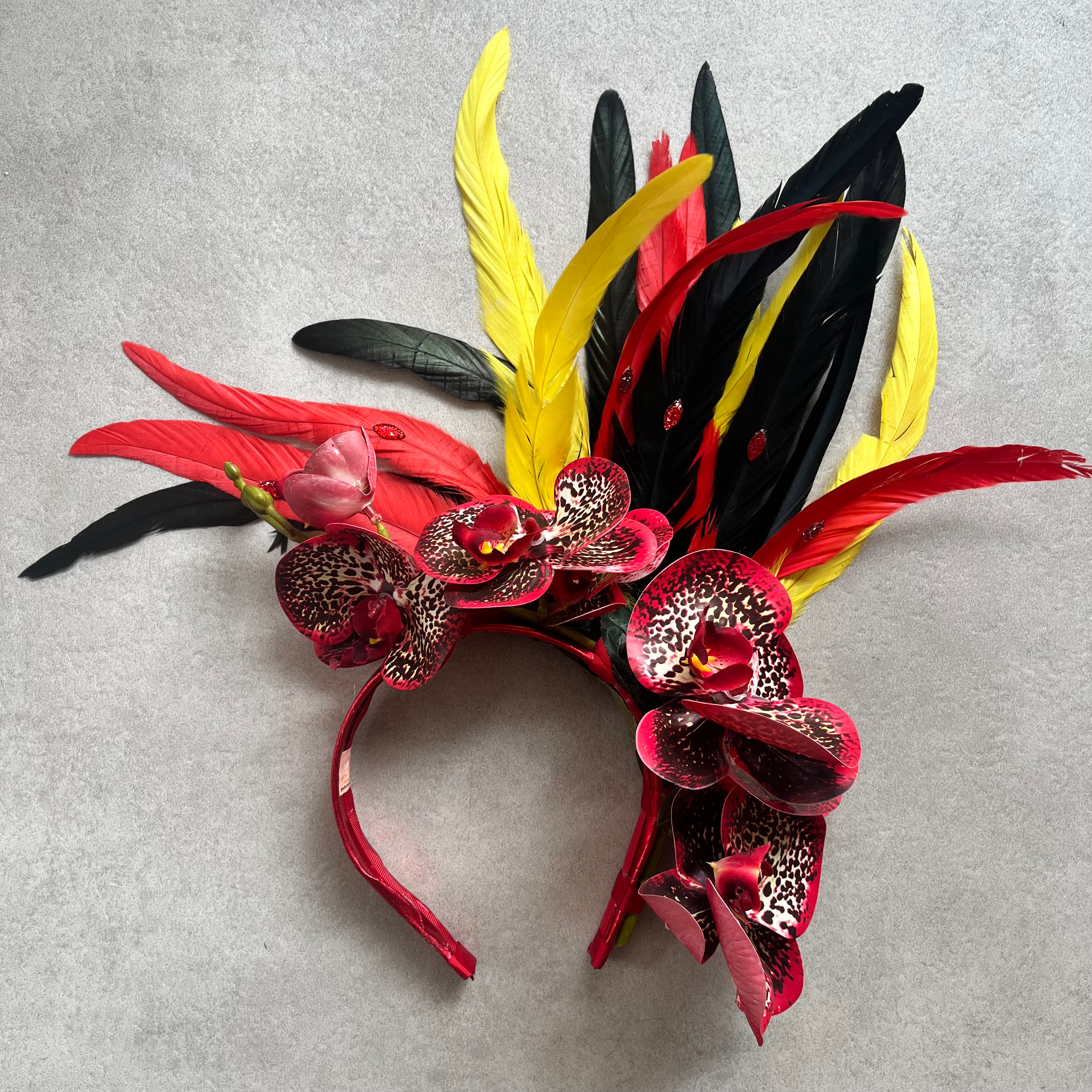 Tiara com orquídeas em preto, amarelo e vermelho e penas combinando, estilo Carnaval.
