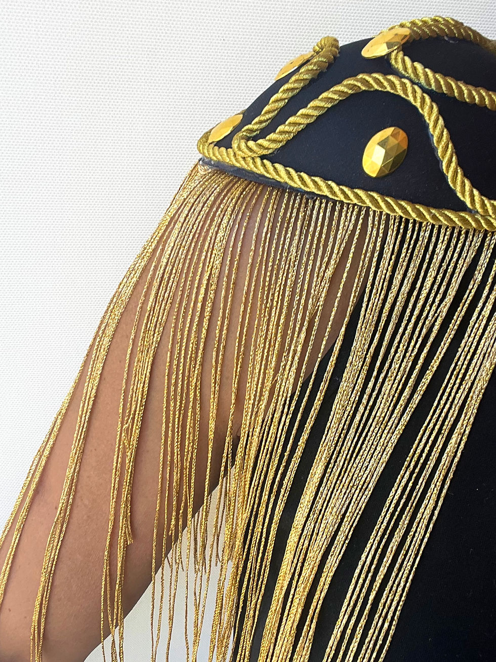 Ombreiras pretas e douradas com franjas longas douradas, cordões dourados, pedras douradas na decoração, fixação bico de pato