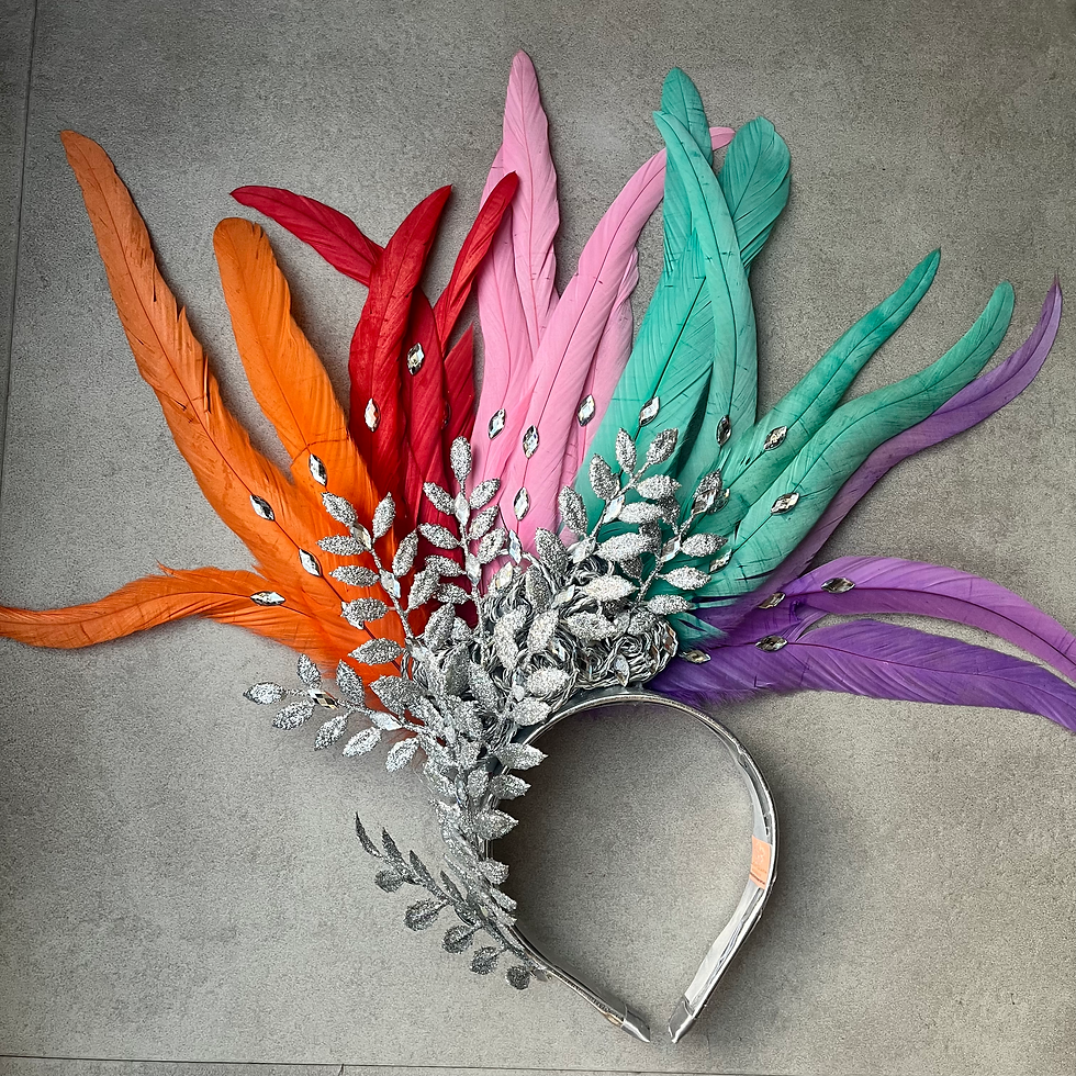 "Tiara de Carnaval com penas coloridas em formato de leque nas cores vermelho, laranja, roxo, verde e rosa, detalhes em prata