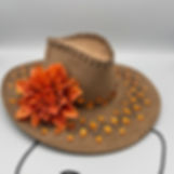 Chapéu estilo boho chic em camurça marrom com flor alaranjada na lateral, detalhes em pedrarias âmbar e cordão ajustável.