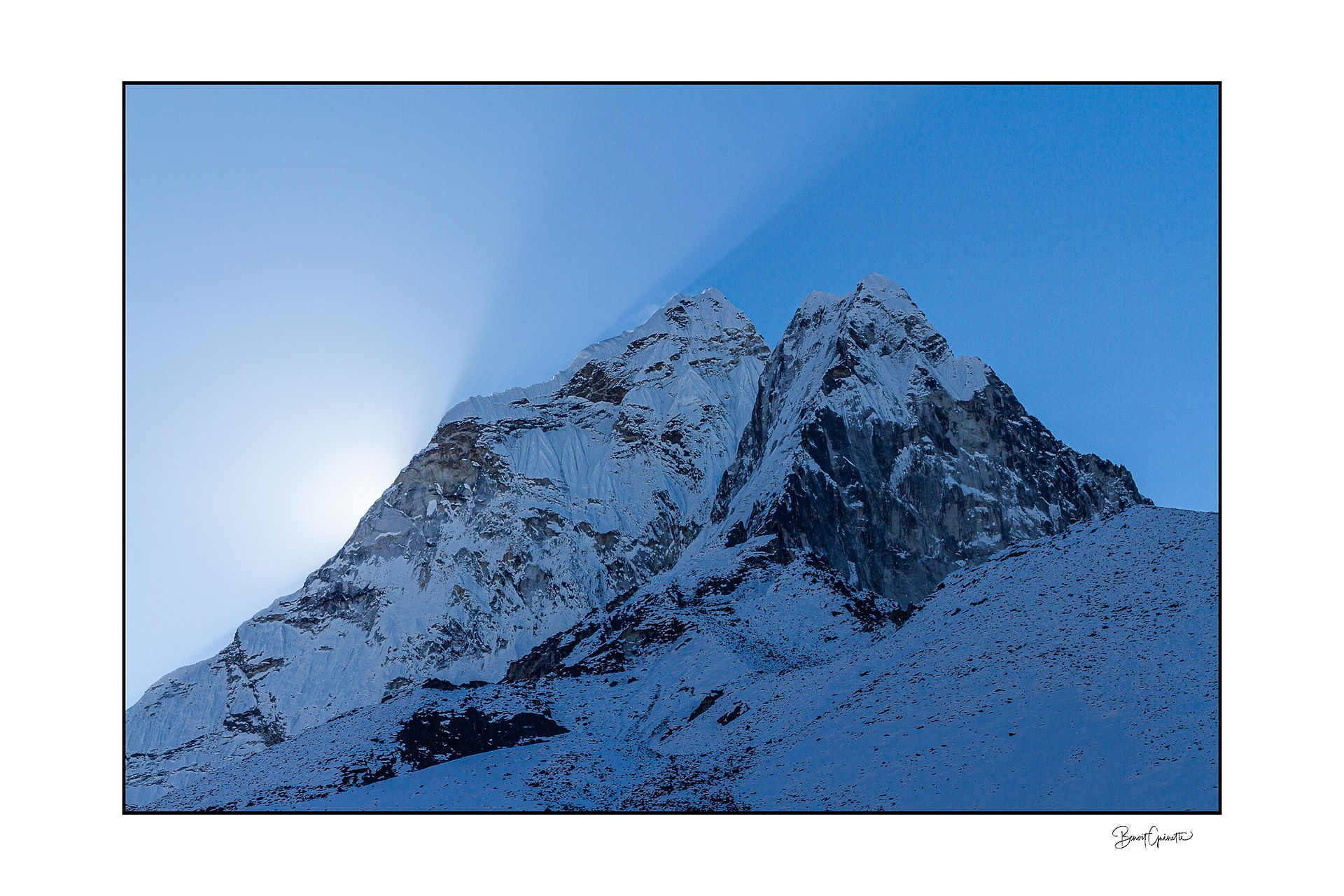Les rayons du soleil levant se découpent en diagonale au‑dessus d’une montagne.