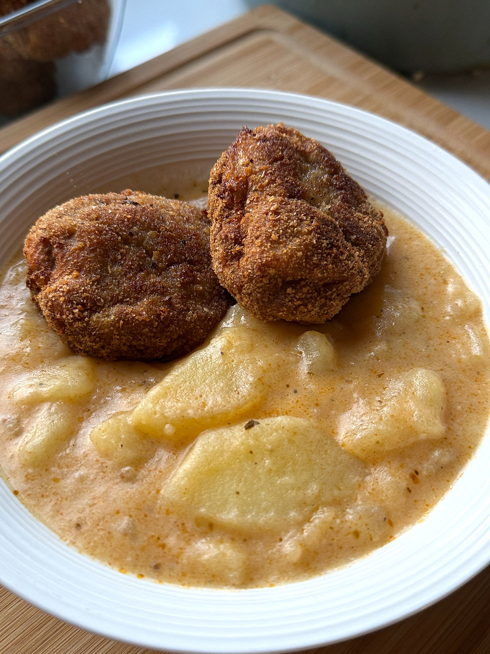 Close-up of creamy Hungarian potato stew topped with three golden breadcrumb-coated beef patties.