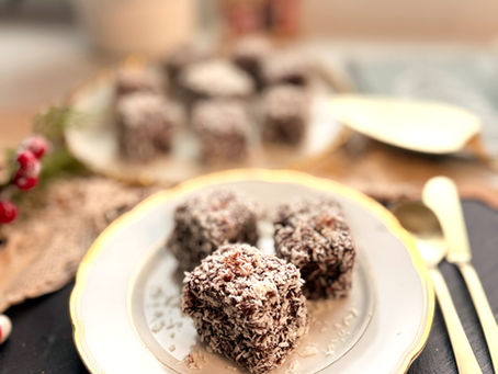Hungarian kókuszkocka dessert on a white plate with gold trim, styled with Christmas decorations