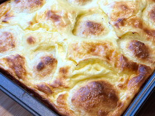 Baked Hungarian farmer cheese dumplings with sour cream topping in a baking dish