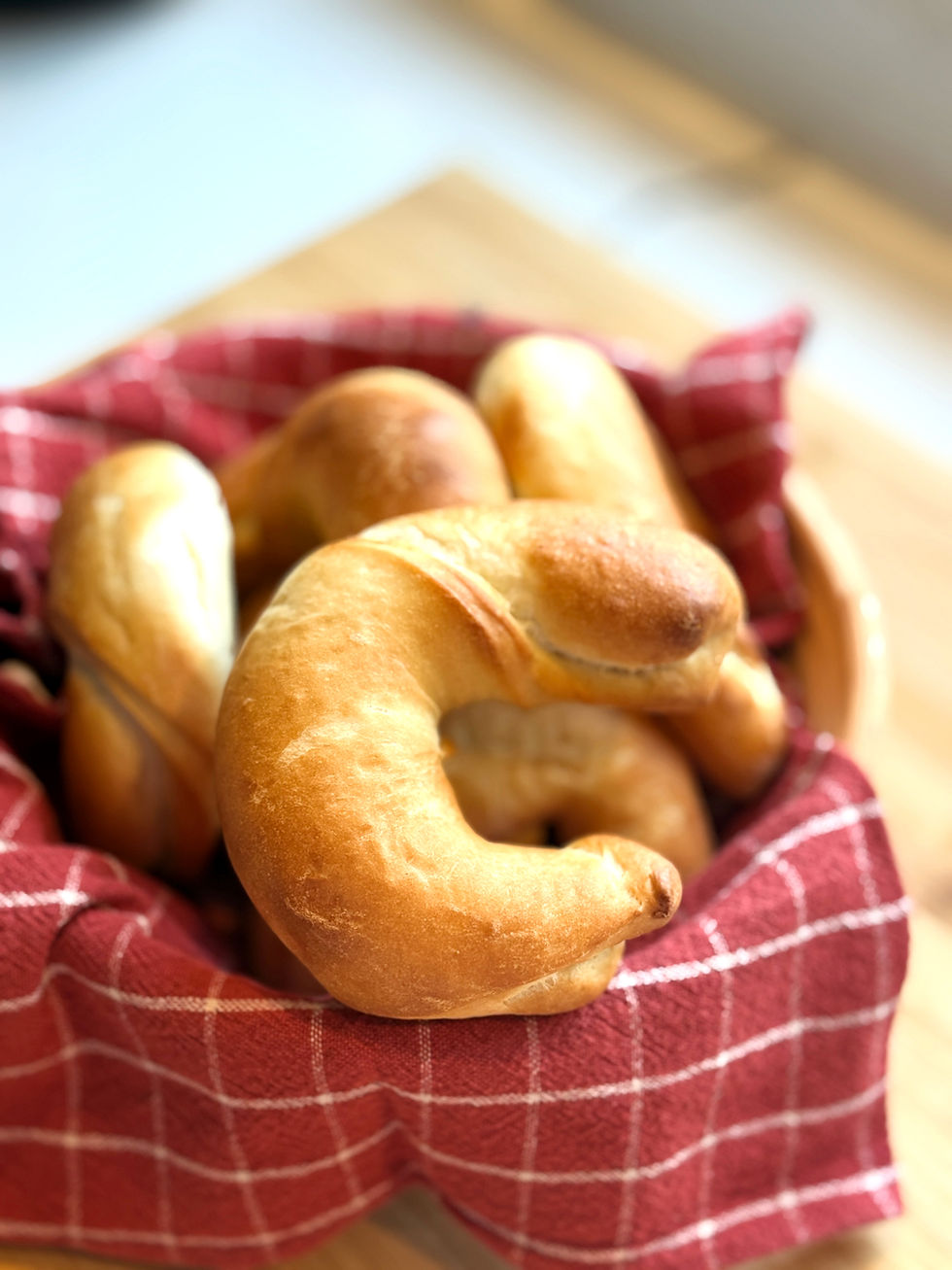Basket of homemade Hungarian no-rise kifli wrapped in a red kitchen towel. Fresh golden crescent rolls ready for breakfast.
