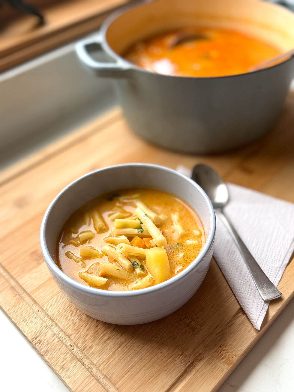 Hungarian creamy yellow wax bean soup with potatoes, carrots and parsley root served in a bowl.