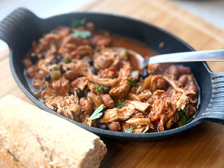 Smoky pulled chicken with black beans and pinto beans served in a cast-iron skillet with fresh crusty bread.