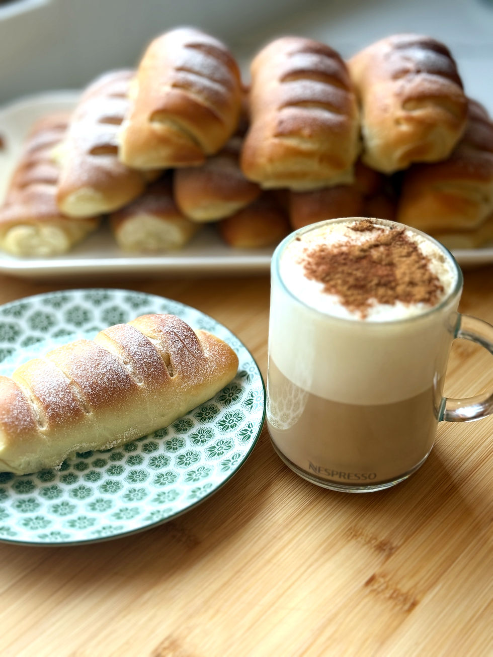 Hungarian farmer’s cheese pastry with powdered sugar served beside a frothy coffee.
