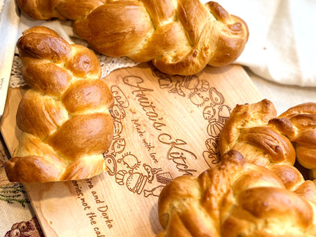 Soft Hungarian Braided Sweet Bread (Foszlós Kalács) cooling on a wooden board in a cozy home kitchen.