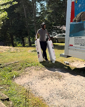 Smiling insulation contractor carrying bags of blown-in insulation to a customer’s home.