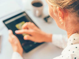A person using a tablet alongside a smartphone