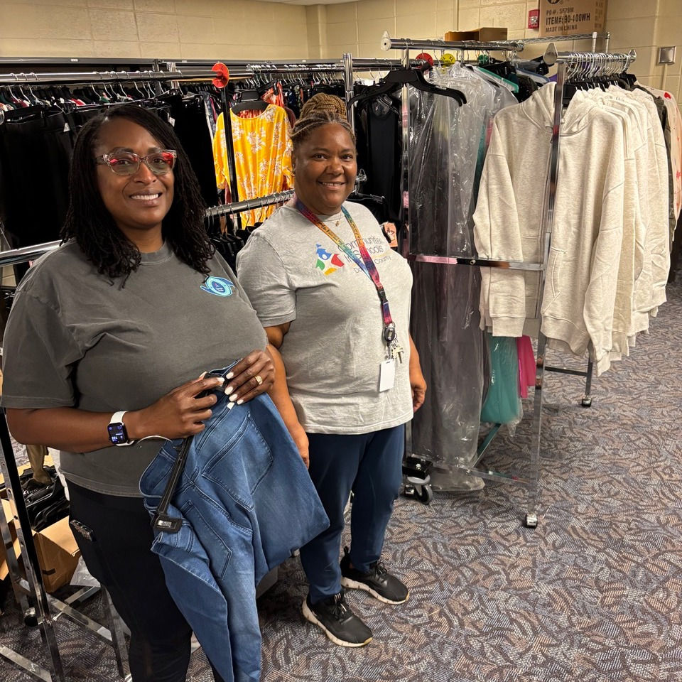 Lorrie Wallace (left), Georgia Power, and Stephanie with Communities in Schools (right) stop to take a pose from hanging clothes in the clothing closet.