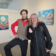 a man and a woman are posing for a picture in front of paintings
