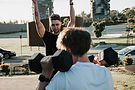 A young personal trainer demonstrates a move to his bootcamp group class.