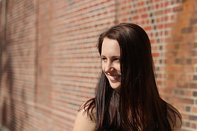 A woman standing in front of a brick wall