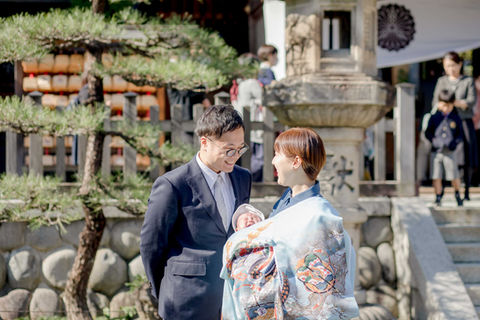 祝着を着た赤ちゃんを抱っこして笑い合う夫婦