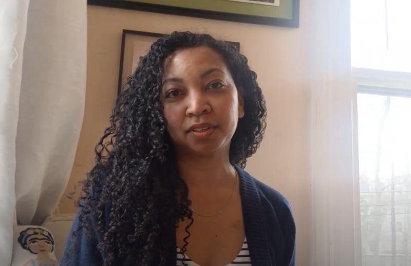 Black woman with long curly hair looks into camera with a smile.