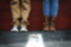 A couple standing side by side against a bold red wall.