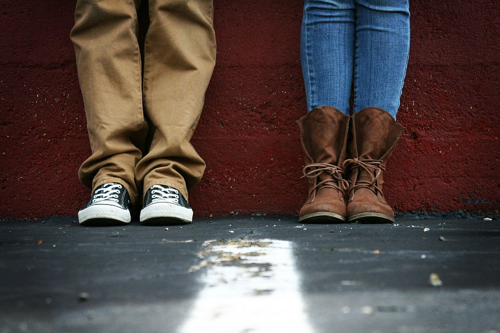 A couple standing side by side against a bold red wall.