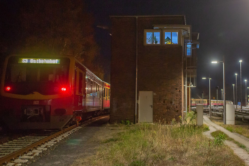 S-Bahn bei Nacht neben einem Stellwerk, in dem eine Kunstinstallation zu sehen ist