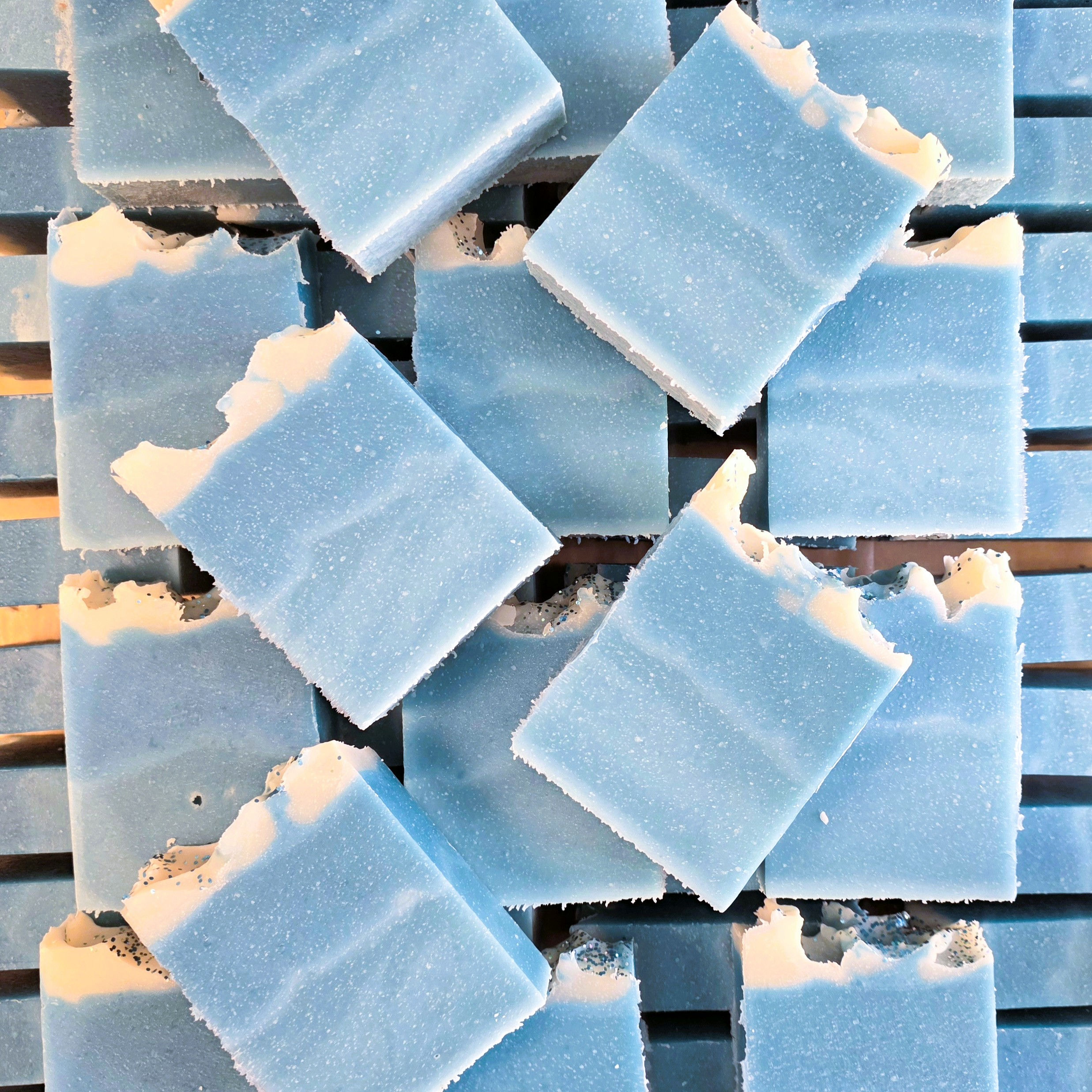 Blue and white soap bars laying flat on soap rows underneath