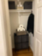 Organized hall closet with neatly arranged bins, shelves, and labeled storage