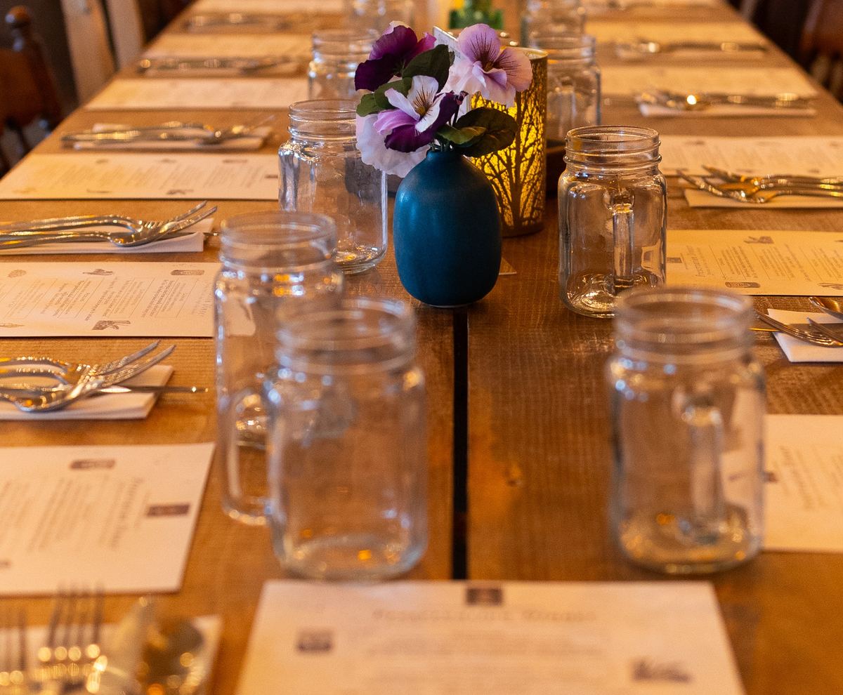The mead hall's long table set with printed menus for a guest chef dinner