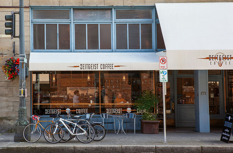 Street view of Zeitgeist Coffee with people inside. Bicycles are parked outside. Red flowers hang nearby. Text: "Zeitgeist Coffee".