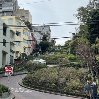 The famous Lombard Street in San Francisco, known for its steep, winding turns lined with colorful flowers and surrounded by city views