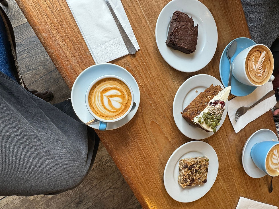 Cappuccinos with latte art, brownies, cakes, and napkins on a wooden table, creating a cozy coffee shop ambiance.