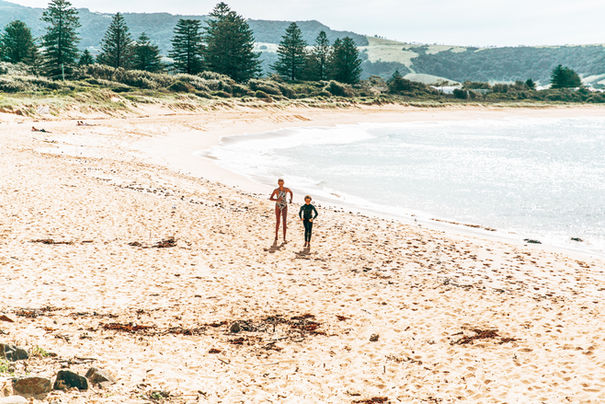 Family walking along Werri Beach near Sundara Beach House beneath soft morning light