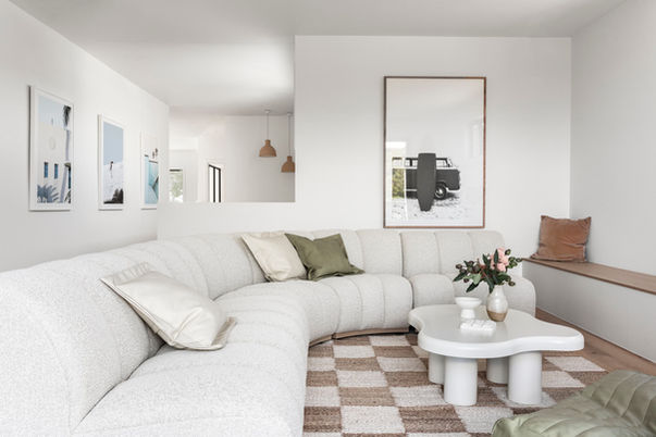 Light-filled living room with curved sofa and coastal artwork