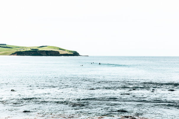 Surfers catching waves at Werri Point minutes from Sundara Beach House