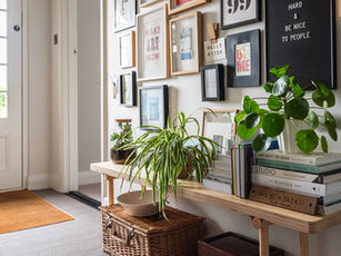 A console table styled with houseplants, books and decorative objects beneath a gallery wall of framed artwork.