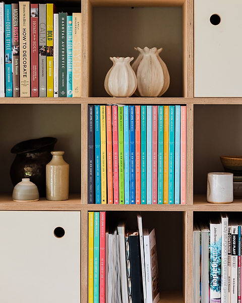 Bespoke birch ply bookcase in 1930s bungalow. Displaying colourful books and magazines, ceramics and decorative objects.