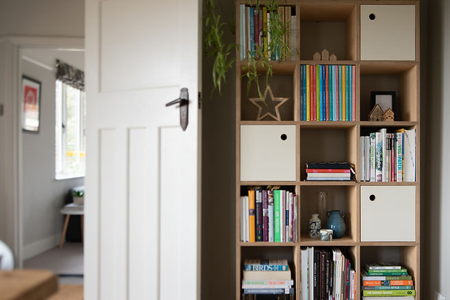 This image shows a plywood bookcase full of colourful books and magazines in a 1930s house.