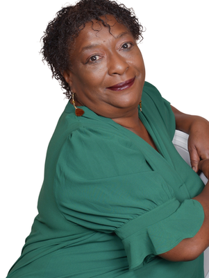 Carman smiling in green dress sitting on a white chair, looking at the camera.
