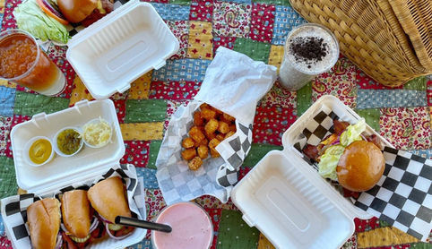 burgers and ice cream shakes and tater tots  on picnic blanket