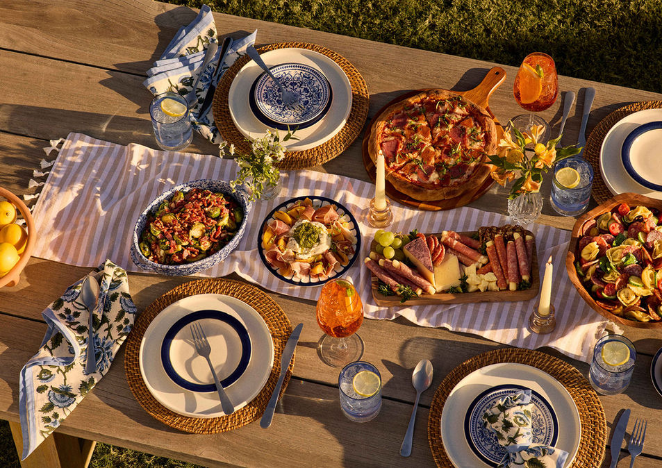 A full dining table spread with charcuterie, pasta, wine, and plates, styled for a shared Italian-inspired meal.