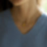 Umbra Blossom pendant necklace in 18K gold worn by model in blue sweater — Menzaman Jewelry