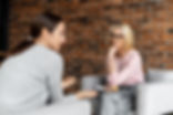 A middle-aged blonde therapist listens intently as her client speaks during a psychotherapy session